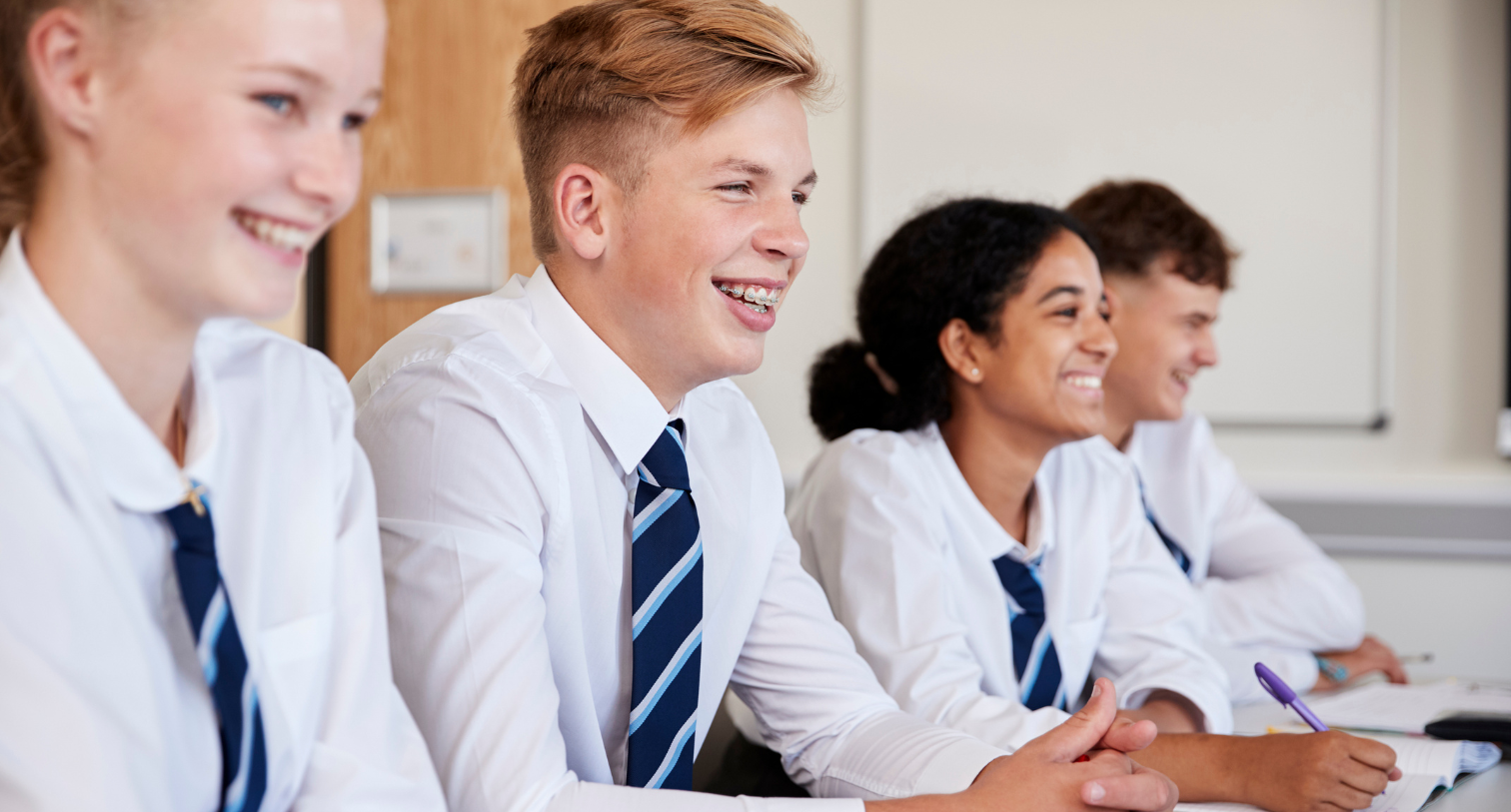 Line of High School Students Wearing Uniform Sitting at Desk in school
