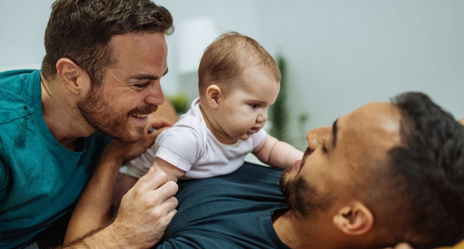 Two dads with their baby and looking happy and smiling