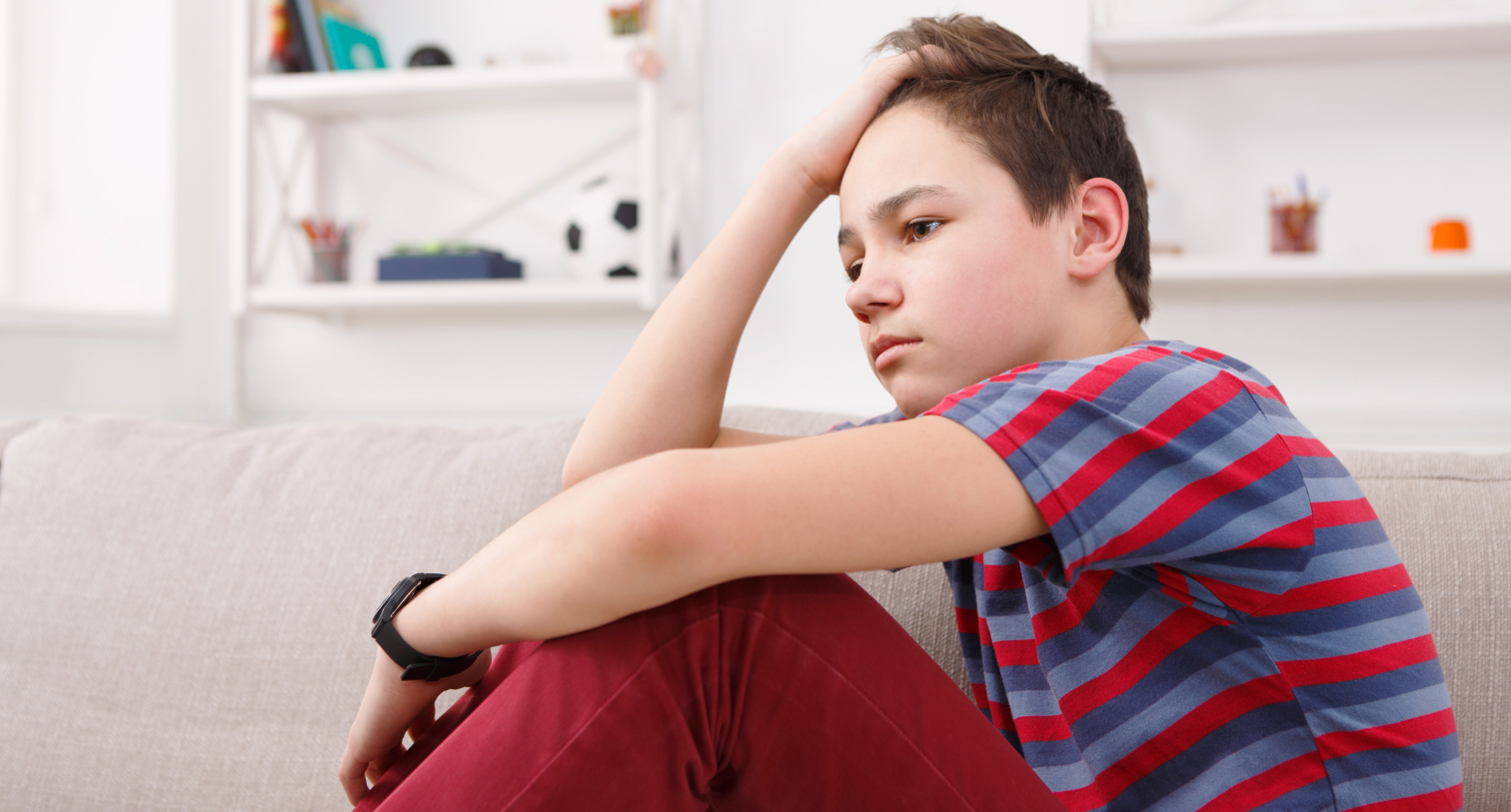 Unhappy teenager looking sad sitting on the floor and staring