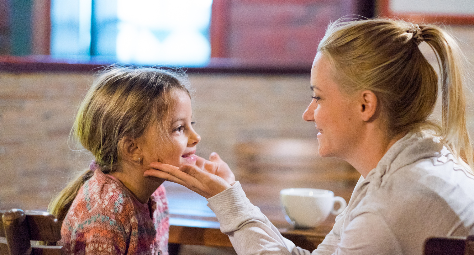 A woman holding a little girls cheeks and smiling together