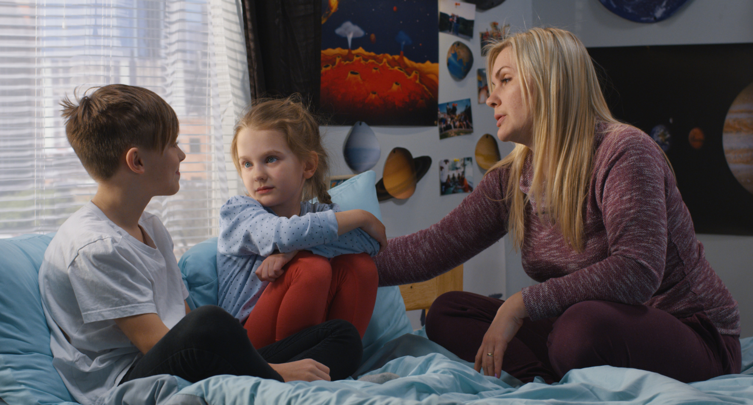 Mother talking and comforting brother and sister in the bedroom