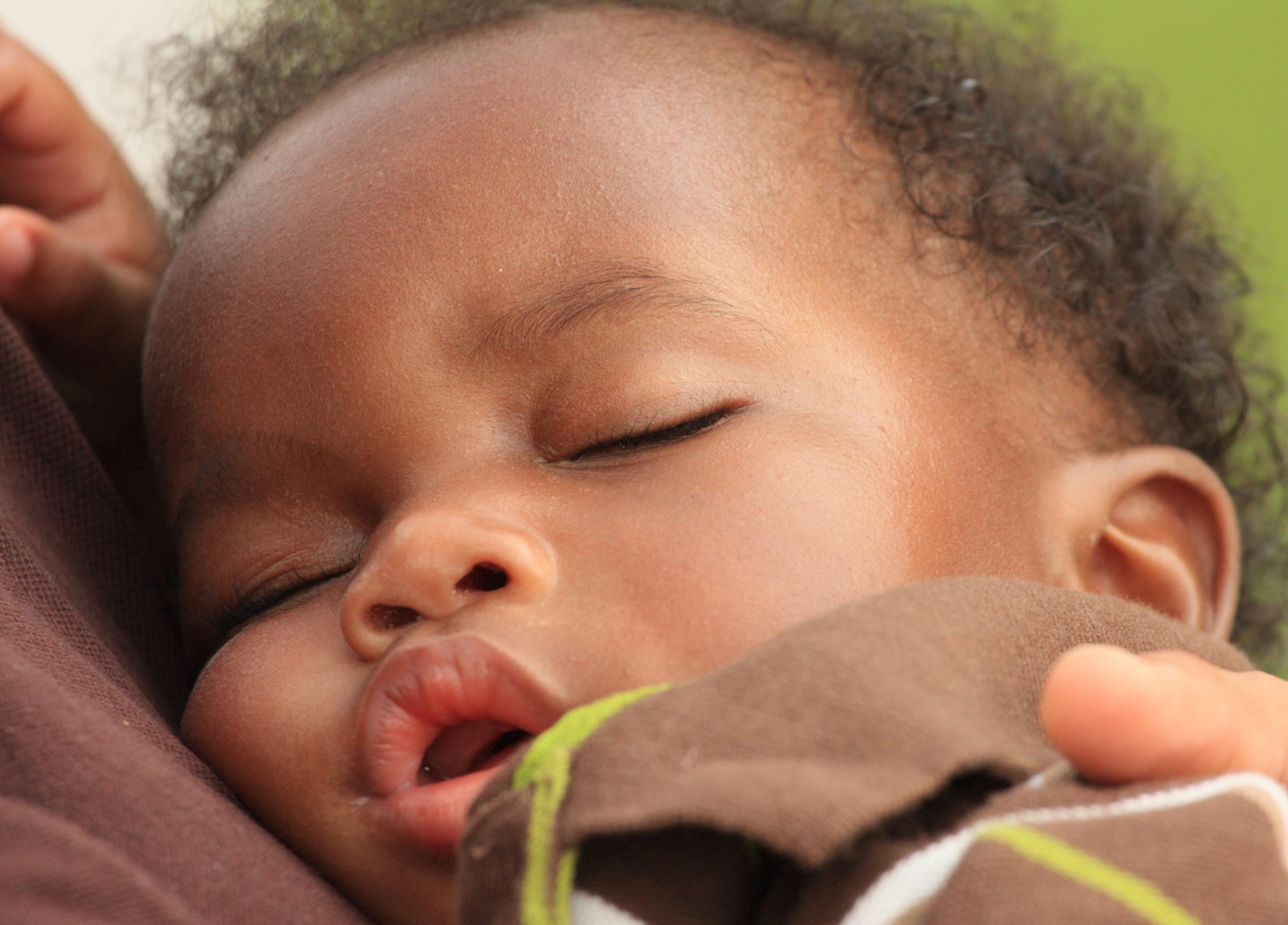 A little baby asleep on their parents chest